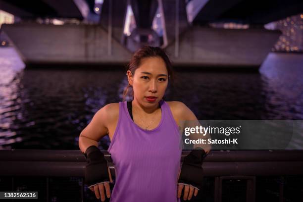 porträt einer jungen athletin, die unter der brücke steht - purpur stock-fotos und bilder