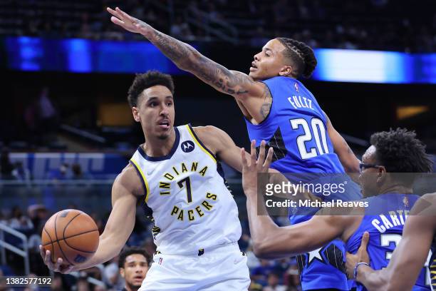 Malcolm Brogdon of the Indiana Pacers throws a pass around Markelle Fultz and Wendell Carter Jr. #34 of the Orlando Magic during the first half at...