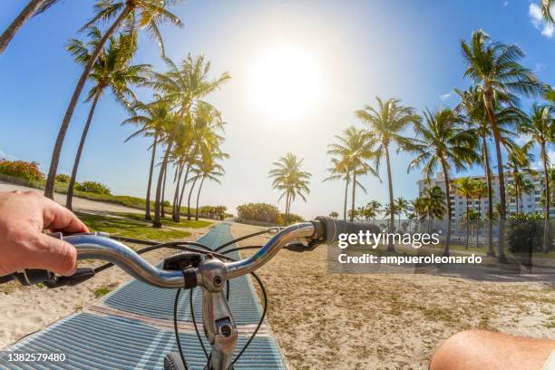 pov standpunktaufnahme eines jungen sportlers, der mit dem fahrrad zum strand in south beach, miami beach, miami, südflorida, vereinigte staaten von amerika fährt - miami fahrrad stock-fotos und bilder