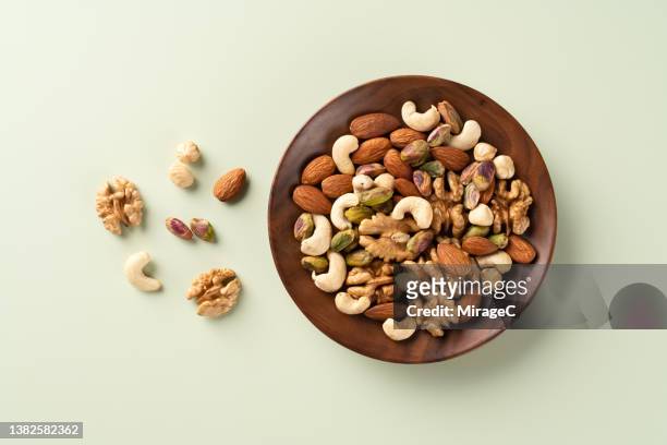 mixed nuts assortment in a wood bowl - snack bowl stock pictures, royalty-free photos & images