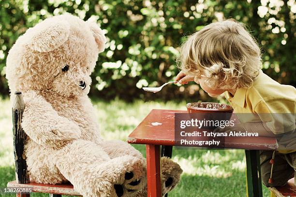 child feeding his teddy bear - child teddy bear stock-fotos und bilder