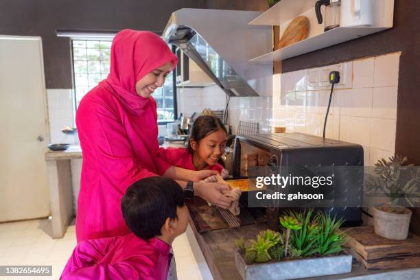 kinder freuen sich über frisch gebackenen kuchen aus dem ofen - muslims prepare for eid in indonesia stock-fotos und bilder
