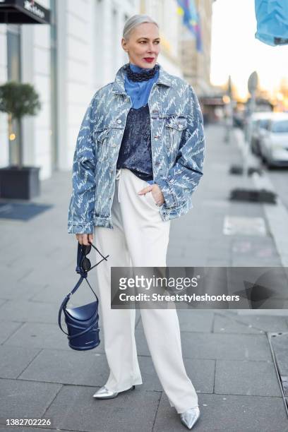 Best Ager Model and Influencer Petra van Bremen wearing a light blue denim jeans jacket with white all over logo print by Balenciaga, a blue blouse...