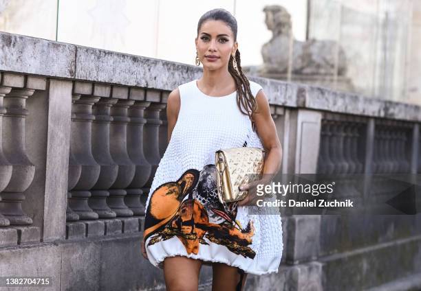 Camila Coelho is seen wearing a white and orange Louis Vuitton dress, gold Louis Vuitton bag and Louis Vuitton boots outside the Louis Vuitton show...
