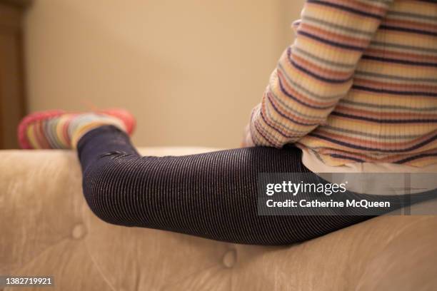 young mixed-race girl perched on top of back of sofa at home watching television - girls in leggings stock-fotos und bilder