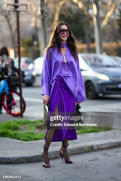 Ece Sukan wears black and purple sunglasses, a purple high neck / cut-out V-neck / oversized silk with inscription print pattern blouse from...