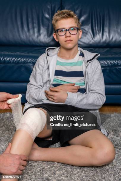 mother bandages her son's injured knee - child bandages stock pictures, royalty-free photos & images