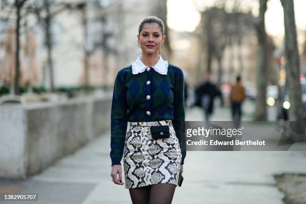 Lala Rudge wears silver and rhinestones earrings, a white shirt with lace collar, a navy blue and dark green checkered / jacquard print pattern...