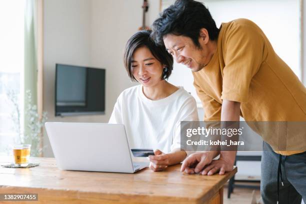 pareja disfruta de compras en línea en casa - casados fotografías e imágenes de stock