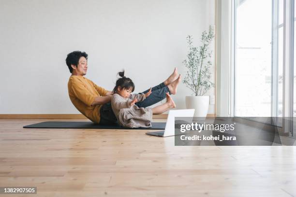 père et descendant exerçant à la maison avec regarder des tutoriels avec l’ordinateur portatif - family yoga photos et images de collection