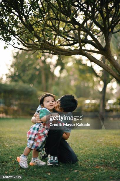 portrait of an elder brother holding his baby brother's hand in a park - sibling stock pictures, royalty-free photos & images