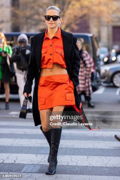 Caroline Daur wearing an orange crop shirt with matching mini skirt, black coat, black boots and black bag, is seen outside Sacai, during Paris...
