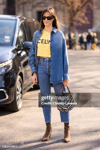 Guest wearing a yellow Celine t-shirt, blue denim shirt, blue jeans, zebra print bag and leopard print boot, is seen outside Sacai, during Paris...