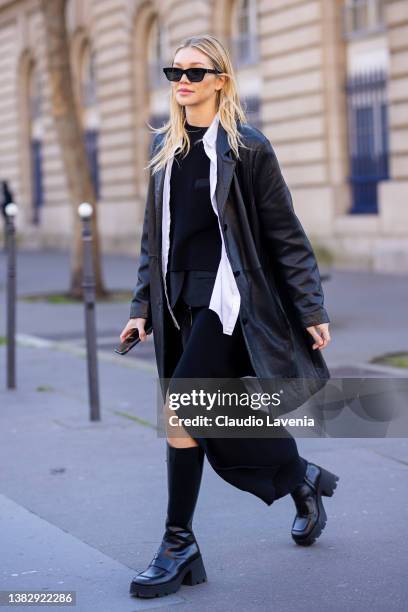 Jessie Andrews wearing a black leather jacket, white shirt, black long dress with front slit and black boots is seen outside Sacai, during Paris...