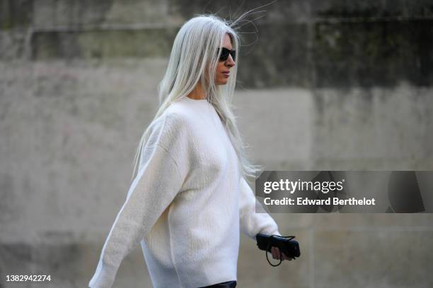 Sarah Harris wears black sunglasses, a white wool pullover, black shiny leather large pants, outside Stella McCartney, during Paris Fashion Week -...