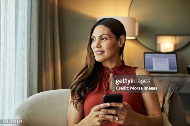 smiling entrepreneur with mobile phone in hotel - 35 39 anos - fotografias e filmes do acervo