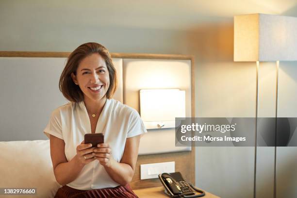 smiling entrepreneur using smart phone in hotel - smart casual - fotografias e filmes do acervo