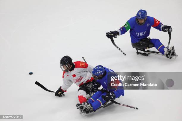 Hongguan Li of Team China and Christoph Depaoli of Team Italy battle for the puck during the Preliminary Round Group B Para Ice Hockey game between...