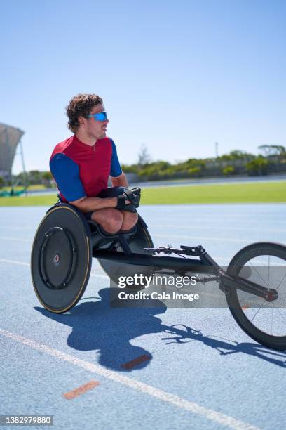 wheelchair athlete on sunny sports track - carrera de sillas de ruedas fotografías e imágenes de stock