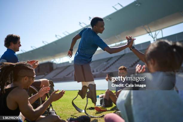 happy male amputee athlete high fiving with friend in stadium - black man high 5 stockfoto's en -beelden