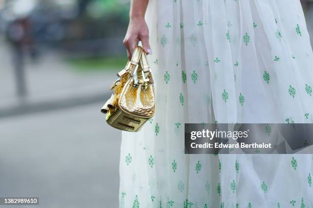 Guest wears a gold shiny leather crocodile print pattern handbag from Giambattista Valli, a high waist with white and green print pattern tulle...