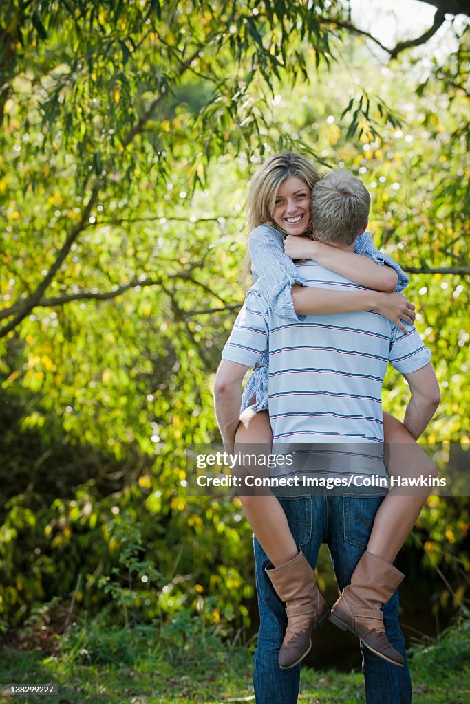 Man carrying girlfriend in park