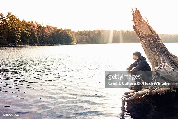 man sitting on boulder by still lake - peterborough ontario fotografías e imágenes de stock