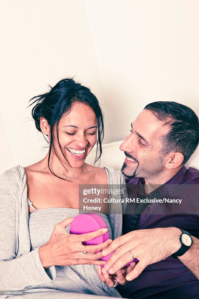 Man giving wife a gift on couch