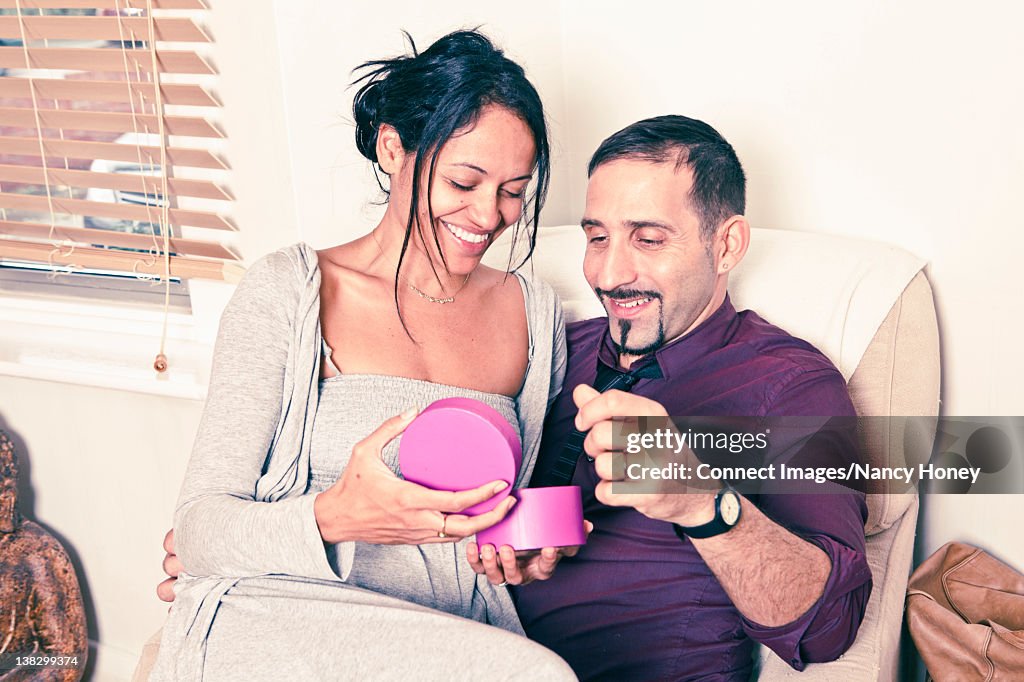 Man giving wife present on couch