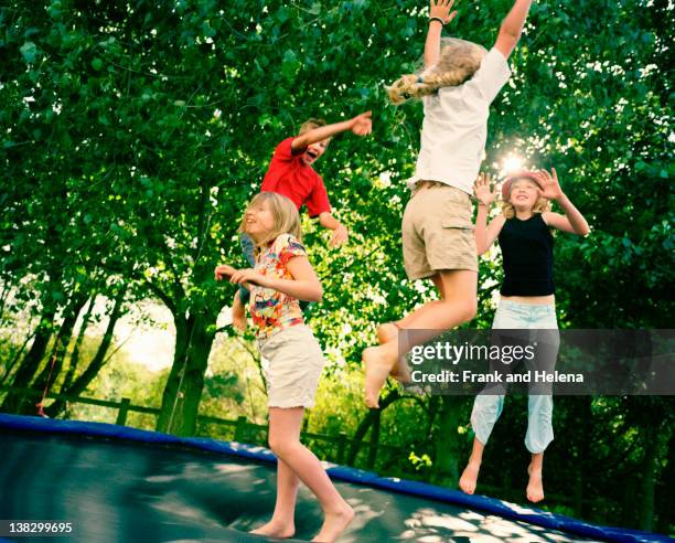 4 children leaping on trampoline - trampoline equipment stock pictures, royalty-free photos & images
