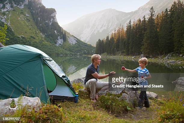 father and son eating at campsite - camping stockfoto's en -beelden