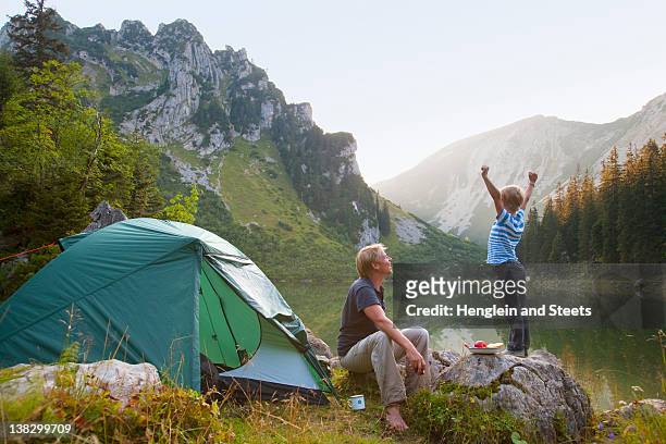 father and son relaxing at campsite - camping photos et images de collection