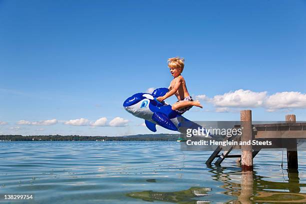 boy jumping into lake with toy whale - leap day stock-fotos und bilder