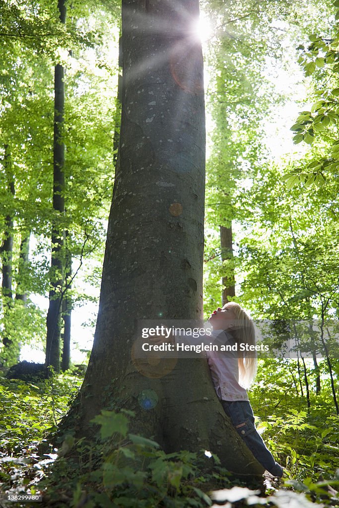 Girl hugging tree in forest