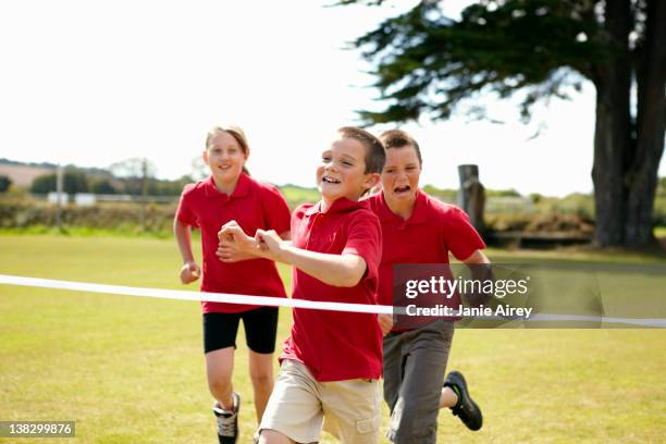 children racing to cross finish line - crossing the finishing line stock pictures, royalty-free photos & images