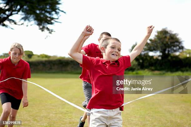 boy cheering and crossing finish line - runner winning stock pictures, royalty-free photos & images