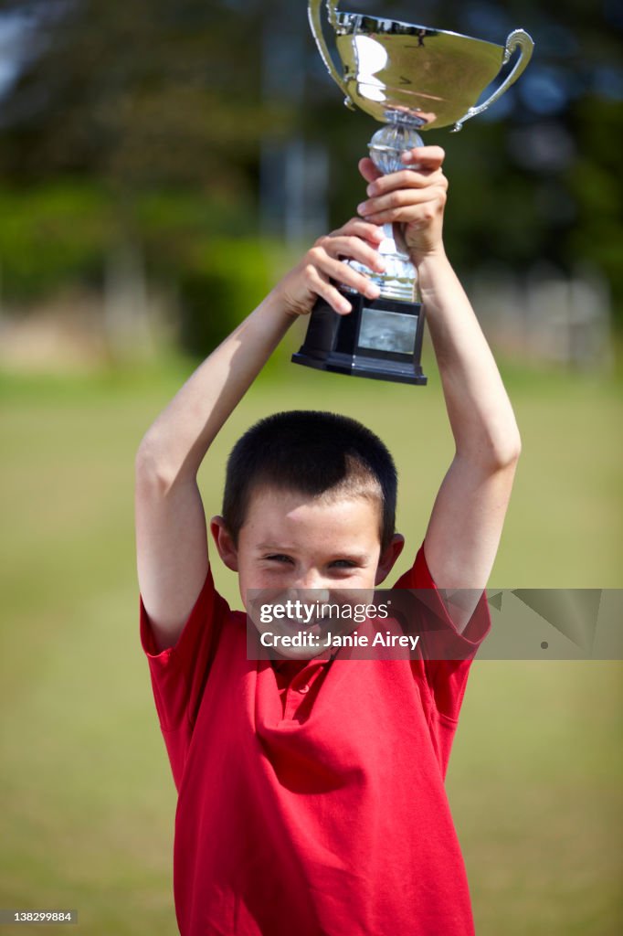 Menino a celebrar com Troféu ao ar livre