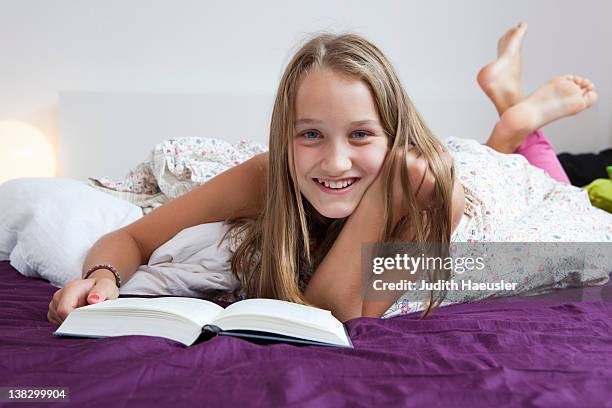 smiling girl reading in bed - barefoot feet up lying down girl stockfoto's en -beelden