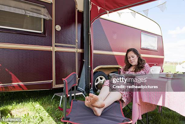 woman reading magazine outside trailer - woman reading magazine stock pictures, royalty-free photos & images