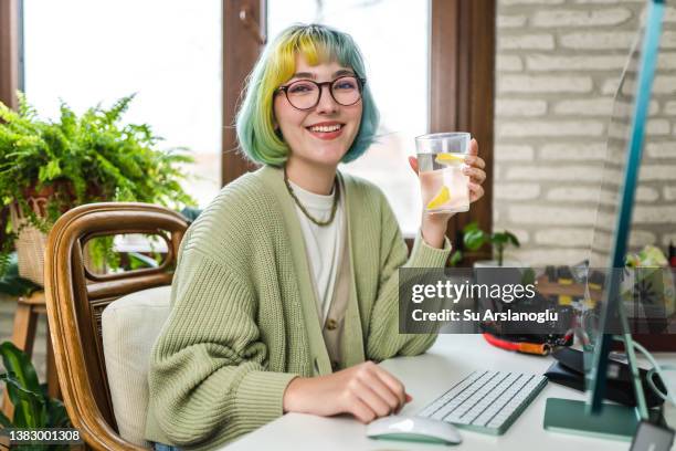 junge frau trinkt wasser während der arbeit - desk woman glasses stock-fotos und bilder