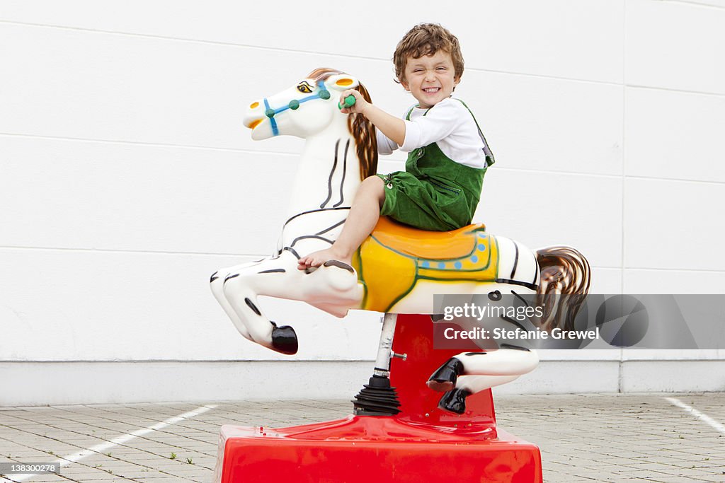 Boy riding mechanical horse outdoors