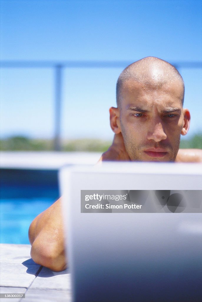 Man using laptop in swimming pool