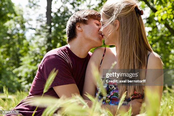 teenage couple kissing in tall grass - young love stock-fotos und bilder