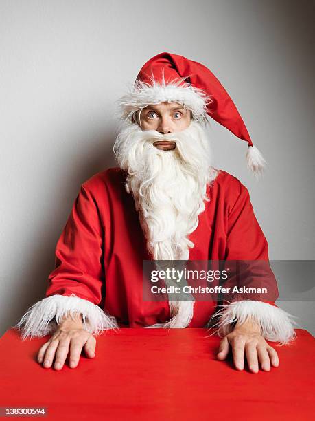 man in santa claus suit sitting at table - santa suit stock pictures, royalty-free photos & images