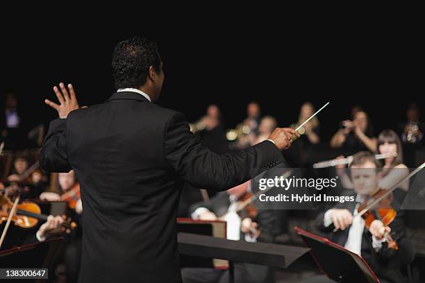 conductor waving baton over orchestra - orkest stockfoto's en -beelden