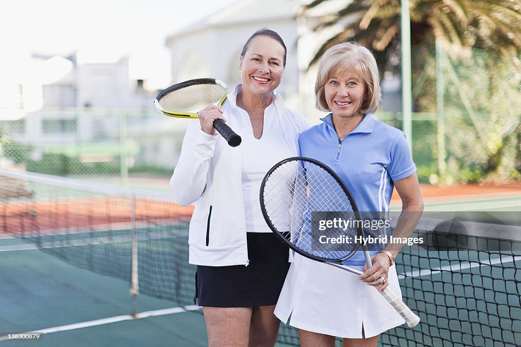 Older women with tennis rackets on court
