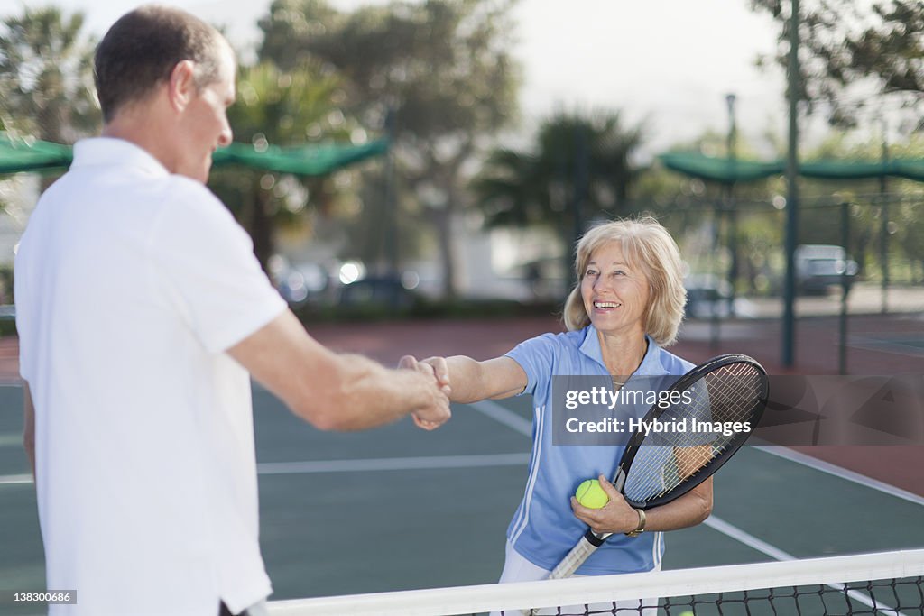 Older couple shaking hands on court