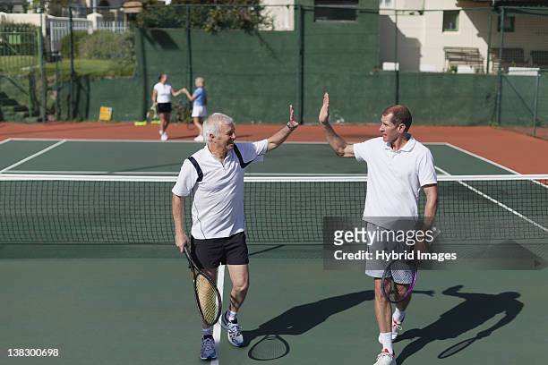 older men high-fiving on tennis court - doubles sports competition format stock pictures, royalty-free photos & images