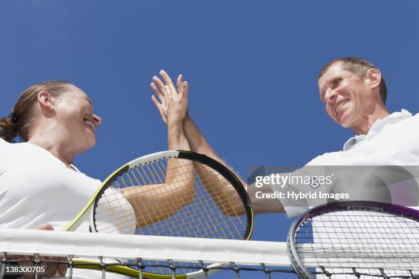 older couple high fiving during tennis - pair stock pictures, royalty-free photos & images