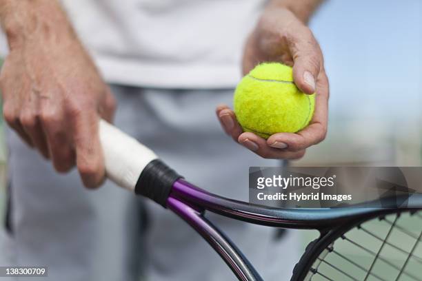 older man holding tennis ball and racket - aufschlagen sport stock-fotos und bilder